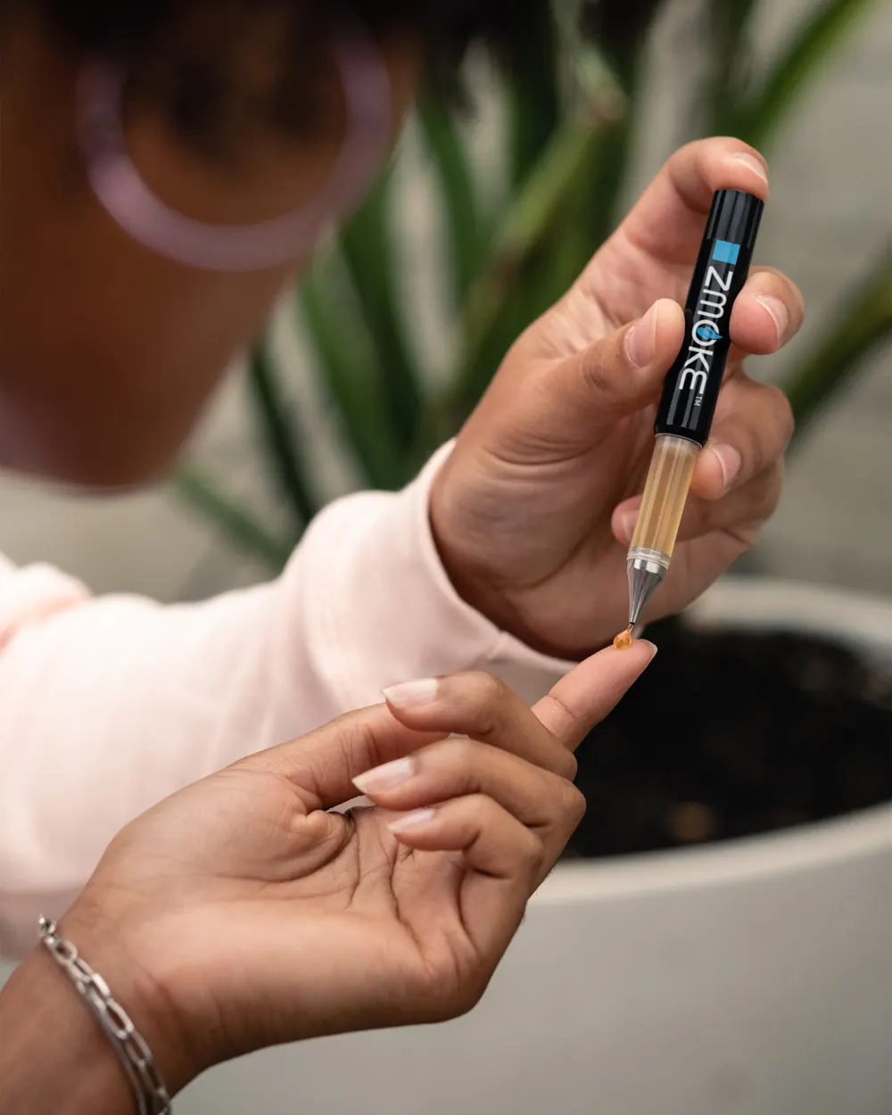 A ZMOKE applicator releasing a single measured drop onto a fingertip